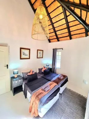 a large bedroom with two beds and a chandelier at Luxury GuesthouseCo HiddenHouse in Marloth Park