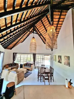 a living room with a wooden ceiling and a table at Luxury GuesthouseCo HiddenHouse in Marloth Park