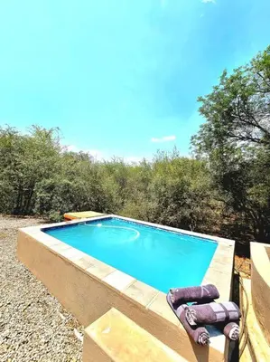 a swimming pool with two lounge chairs next to it at Luxury GuesthouseCo HiddenHouse in Marloth Park