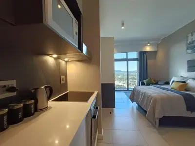 a bedroom with a bed and a kitchen with a sink at Comfort at 1320 Menlyn Maine Residences in Pretoria