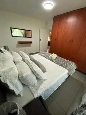 a bedroom with a bed with pillows and a cabinet at The Lake Villa in Benoni