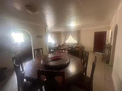 a dining room and living room with a table and chairs at The Lake Villa in Benoni