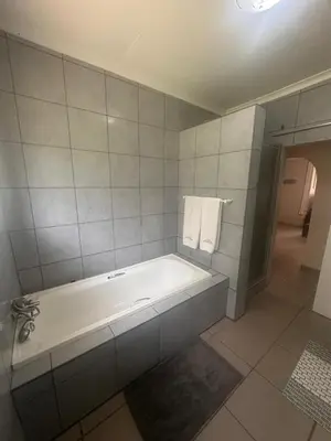 a white bathroom with a tub and towels on the wall at The Lake Villa in Benoni