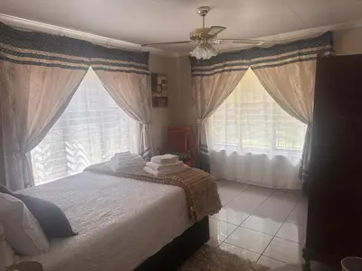 a bedroom with a bed and two large windows at The Lake Villa in Benoni