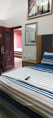 a bedroom with a large bed with blue and white sheets at Whitehouse Lodge Benoni in Benoni