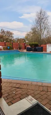a large swimming pool with blue water at Whitehouse Lodge Benoni in Benoni