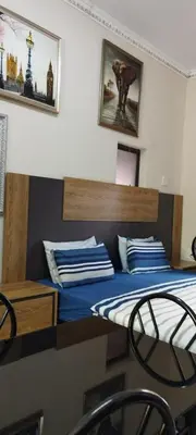 a bedroom with a bed with blue sheets and pictures on the wall at Whitehouse Lodge Benoni in Benoni