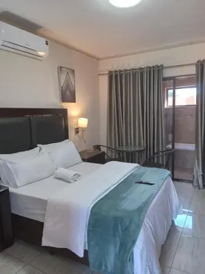 a bedroom with a large white bed and a window at Whitehouse Lodge Benoni in Benoni