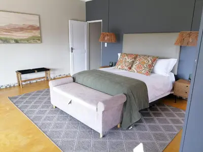 a bedroom with a bed and a couch and a chair at Shingalana Cottages in White River