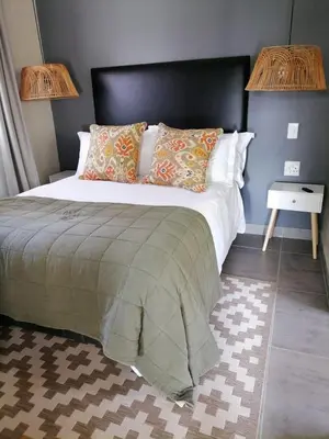 a bedroom with a large bed with a black headboard at Shingalana Cottages in White River