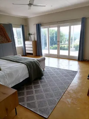 a bedroom with a bed and a large window at Shingalana Cottages in White River