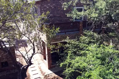 a brick building with a bridge in the middle of trees at Melamar Estate in Marloth Park