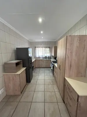 a kitchen with wooden cabinets and a black refrigerator at Melamar Estate in Marloth Park
