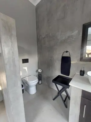 a bathroom with a toilet and a sink and a table at House UmGanu in Marloth Park