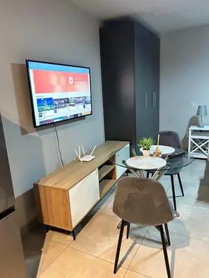 a living room with a table and a tv at Circa Lynnwood Studio in Pretoria