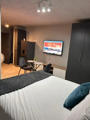 a bedroom with a bed and a flat screen tv at Circa Lynnwood Studio in Pretoria