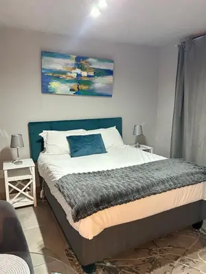 a bedroom with a large bed with a blue headboard at Circa Lynnwood Studio in Pretoria