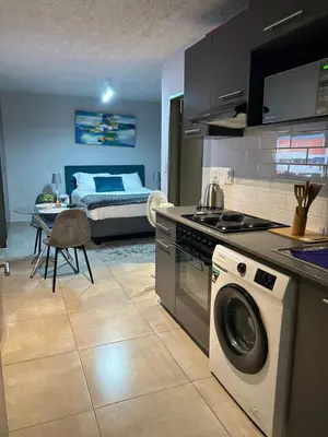 a kitchen and living room with a bed and a washing machine at Circa Lynnwood Studio in Pretoria