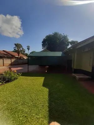 a yard of a house with a green building at Buffalo Street Cottages in Malelane