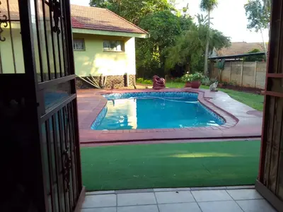 an open door to a swimming pool in a yard at Buffalo Street Cottages in Malelane