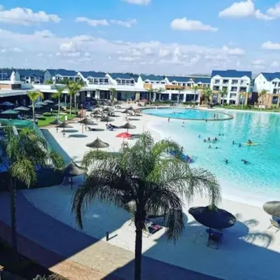 a large swimming pool with palm trees in a resort at The Blydes Pretoria in Pretoria