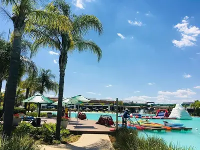 a group of boats in a pool with palm trees at The Blydes Pretoria in Pretoria