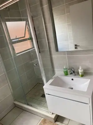 a bathroom with a shower and a white sink at The Blydes Pretoria in Pretoria