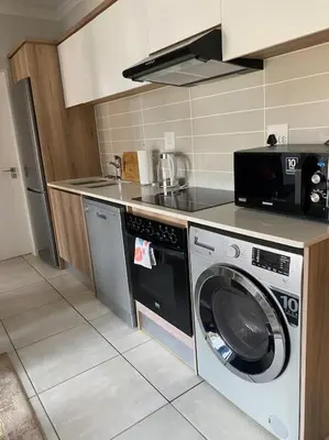 a kitchen with a washing machine and a microwave at The Blydes Pretoria in Pretoria