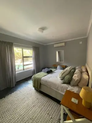 a bedroom with a bed and a desk and a window at African Vibes in Marloth Park