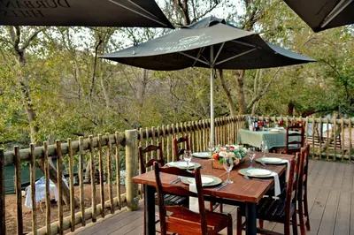a wooden table with an umbrella on a deck at Thanda Manzi Country Hotel in Centurion