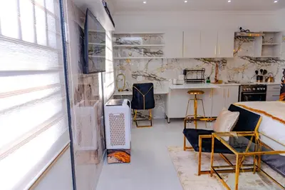 a bedroom with a bed and a kitchen with a window at Homes of Ace Studio 1 in Pretoria