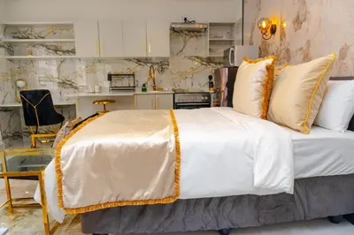 a bedroom with a bed with white and gold pillows at Homes of Ace Studio 1 in Pretoria