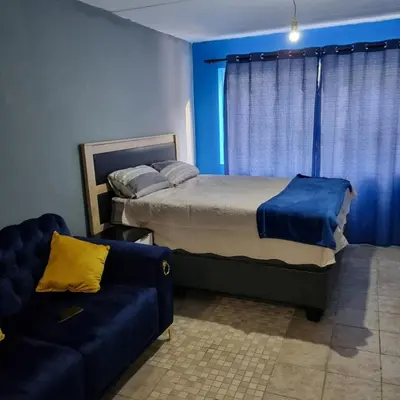 a bedroom with a bed and a couch at Greggs Place at Capital Hill Arcadia in Pretoria