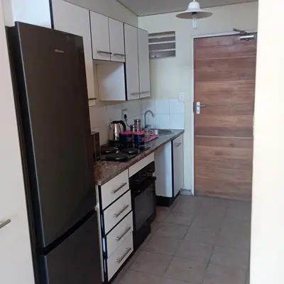 a kitchen with a black refrigerator and white cabinets at Greggs Place at Capital Hill Arcadia in Pretoria