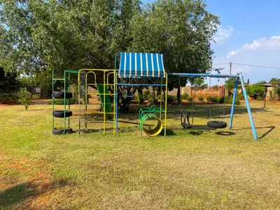 a playground with a blue and white chair and swings at Bobisemo Lux Guesthouse in Tierpoort