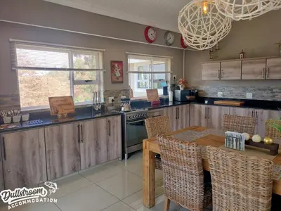 a kitchen with wooden cabinets and a table with chairs at Misty View House in Dullstroom