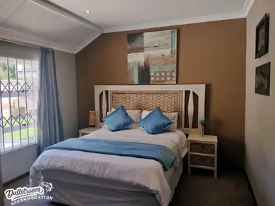 a bedroom with a large bed with blue pillows at Misty View House in Dullstroom
