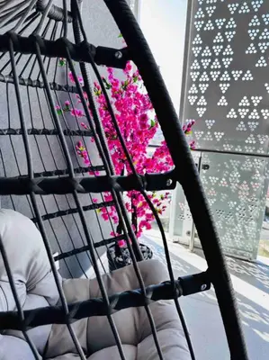 a woman sitting in a chair with pink flowers in a window at Waterfall Peaceful Oyster in Midrand