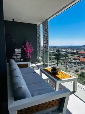 a living room with a couch and a table on a balcony at Waterfall Peaceful Oyster in Midrand