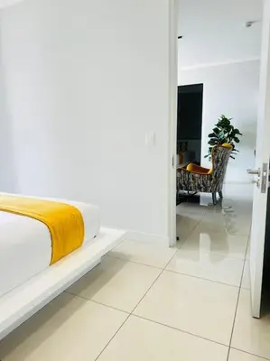 a white bedroom with a bed and a chair at Waterfall Peaceful Oyster in Midrand