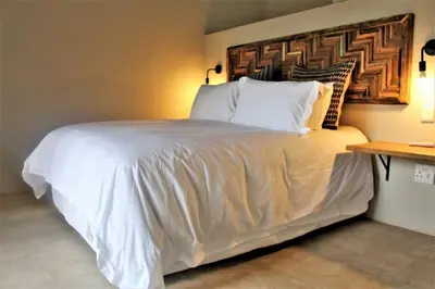 a bedroom with a white bed with a wooden headboard at Ebony House - Kruger National Park in Hectorspruit