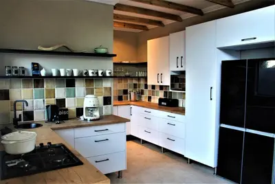 a kitchen with white cabinets and a black refrigerator at Ebony House - Kruger National Park in Hectorspruit