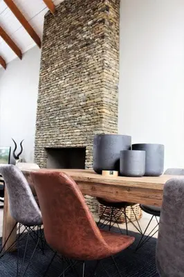 a living room with a table and chairs and a brick fireplace at Ebony House - Kruger National Park in Hectorspruit