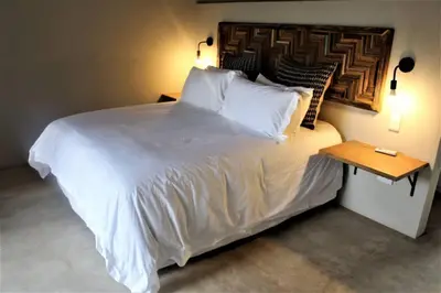 a bedroom with a large white bed with a wooden headboard at Ebony House - Kruger National Park in Hectorspruit