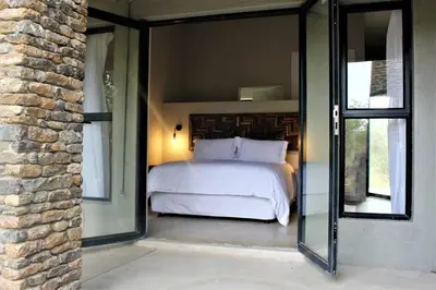 a bedroom with a bed and a glass doorway at Ebony House - Kruger National Park in Hectorspruit