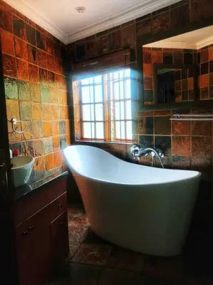 a bathroom with a large tub and a sink at The Yellow House in Brits