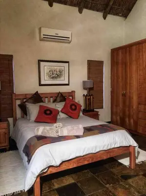 a bedroom with a bed with red pillows on it at The Yellow House in Brits
