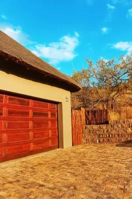 a garage with red doors and a stone wall at The Yellow House in Brits