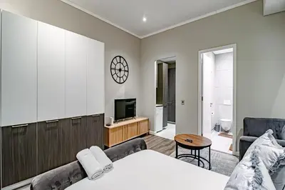 a bedroom with a bed and a tv and a couch at Penthouse and Apartment at The Capital Triology Menlyn Maine in Pretoria