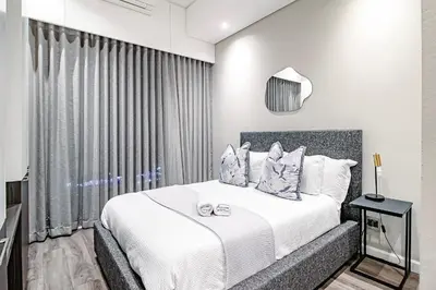 a bedroom with a bed with white sheets and pillows at Penthouse and Apartment at The Capital Triology Menlyn Maine in Pretoria